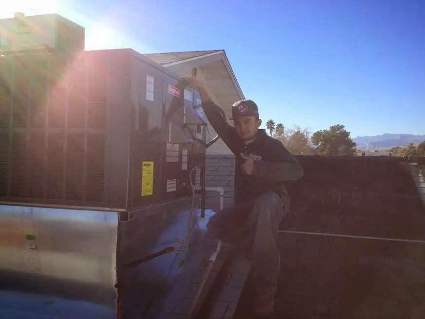 HVAC technician performing HVAC Inspection on a rooftop unit in Muskegon